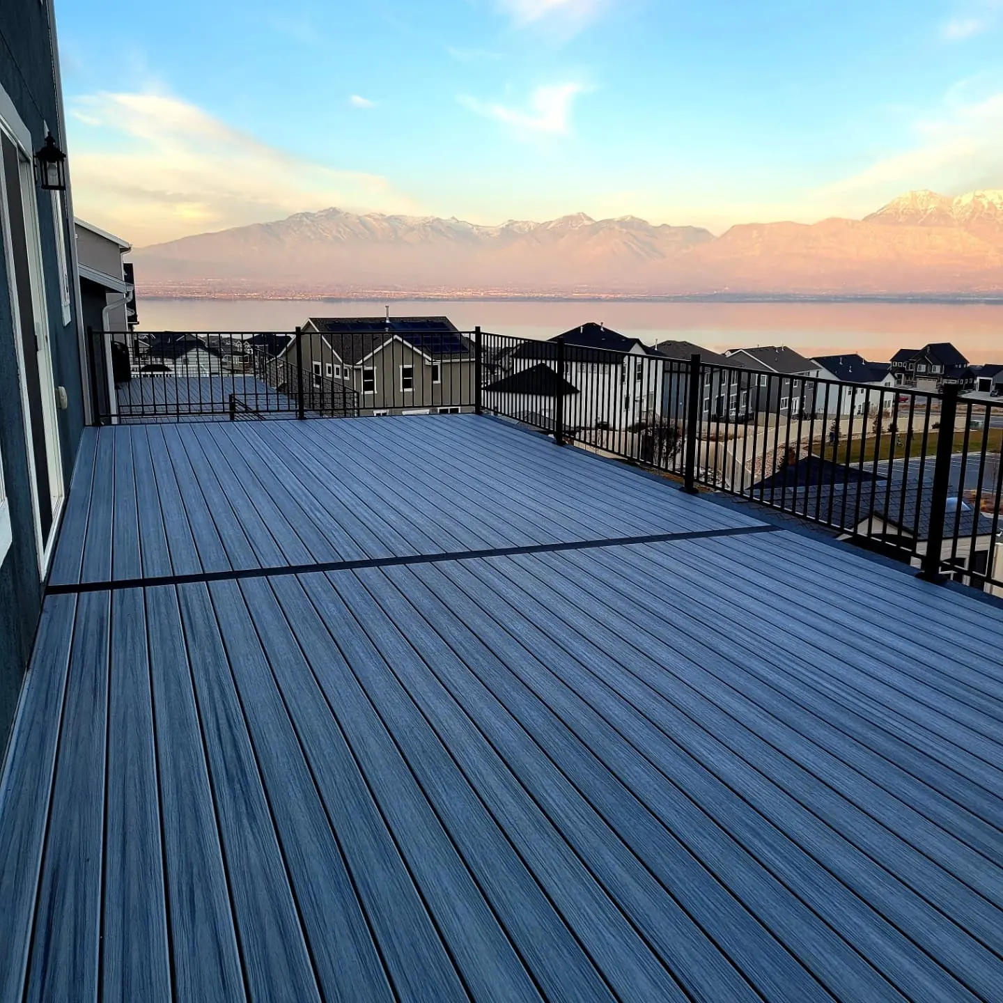 Blue-gray composite deck with black railing at sunset