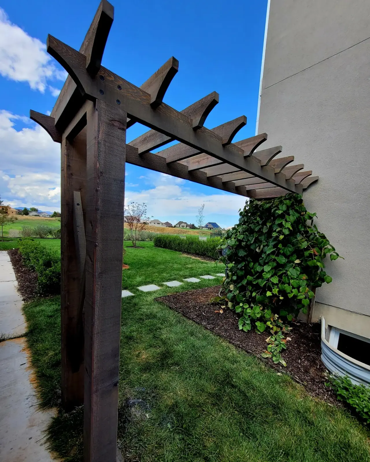 Stained wood trellis arbor in a backyard