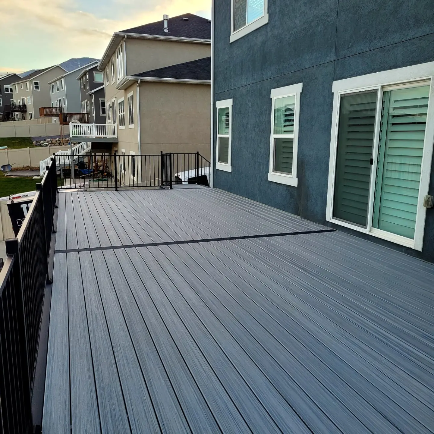 Gray composite deck with black aluminum railing along the house