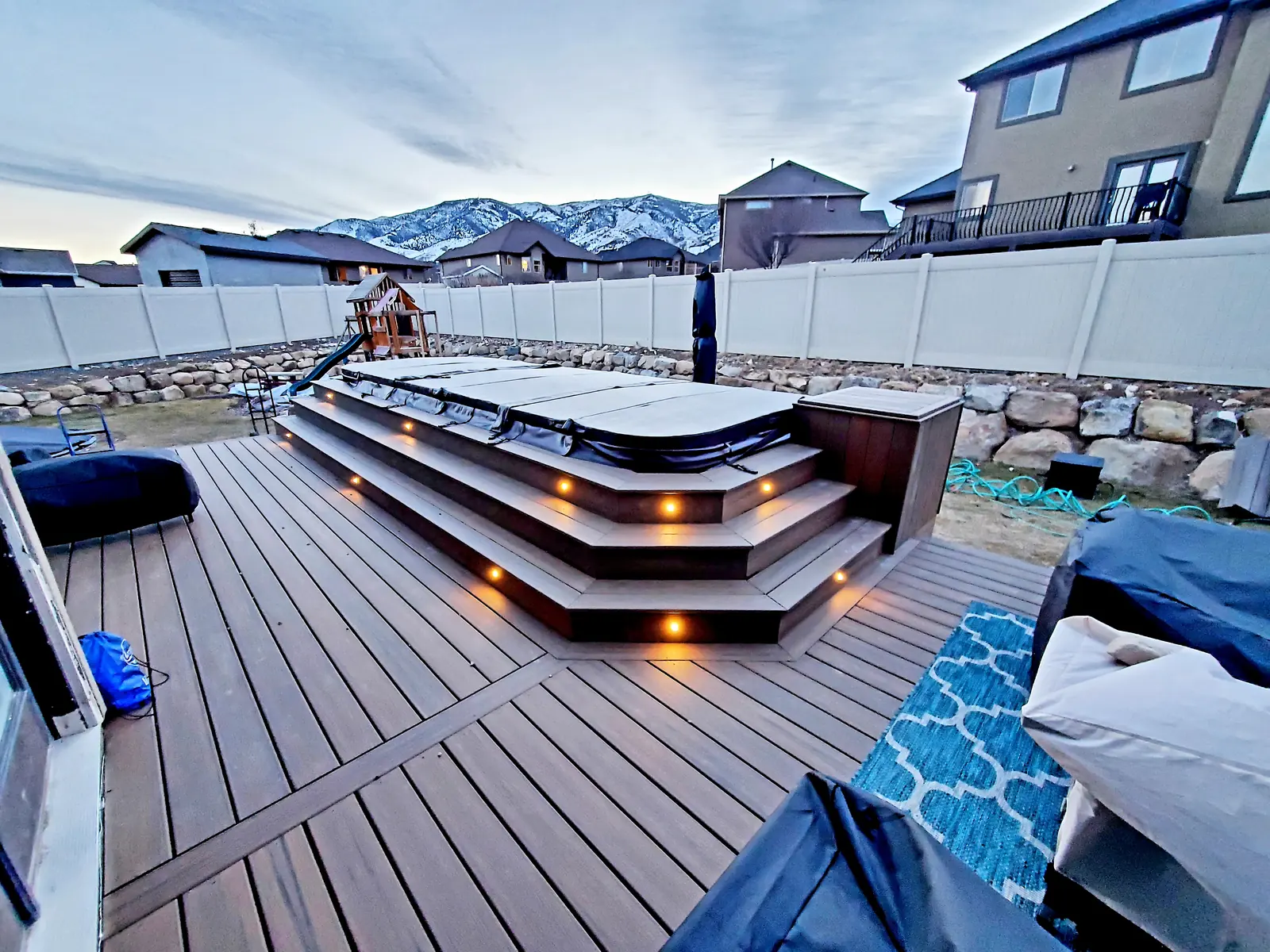 Built-in hot tub surround with lit steps on a composite deck
