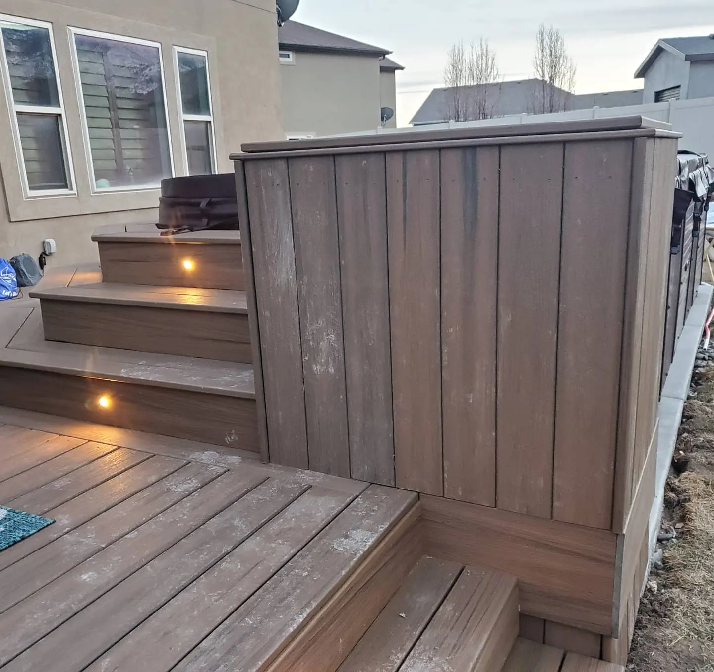Composite privacy wall beside lit deck steps