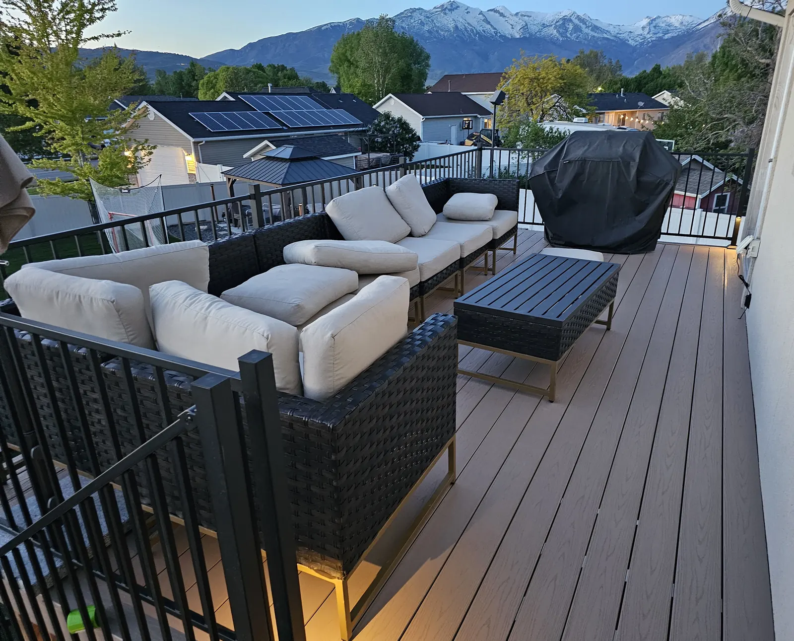 Outdoor sectional on a composite deck with a mountain view at dusk