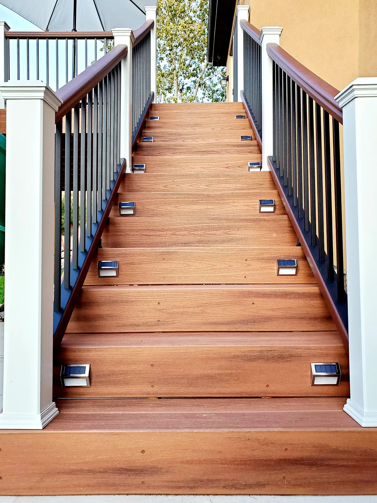 Composite deck stairs with solar step lights and white posts