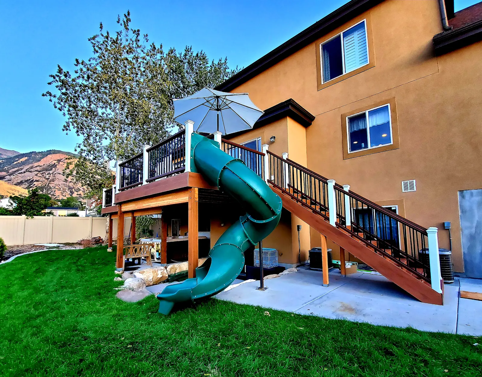 Green spiral tube slide from a second-story deck to the lawn