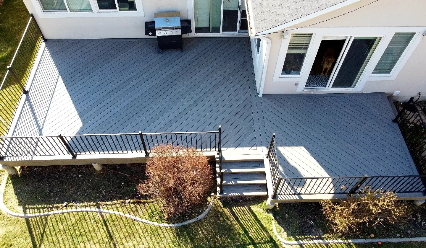 Aerial view of a gray composite deck with diagonal boards, picture frame border and black railing