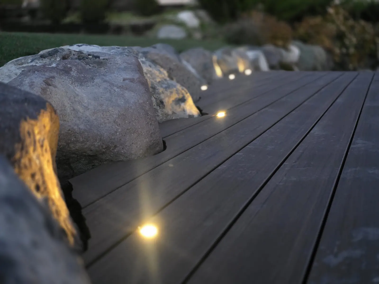 Recessed deck lights along a boulder edge at dusk