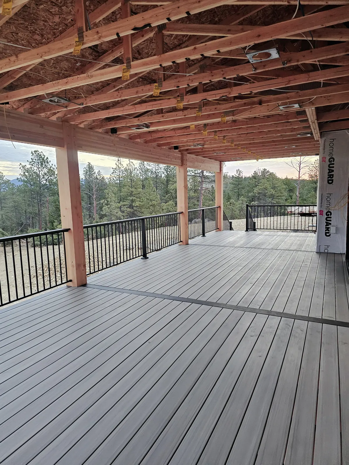 Covered deck in TimberTech American Walnut with a breaker board and black Fortress steel railing overlooking pine trees