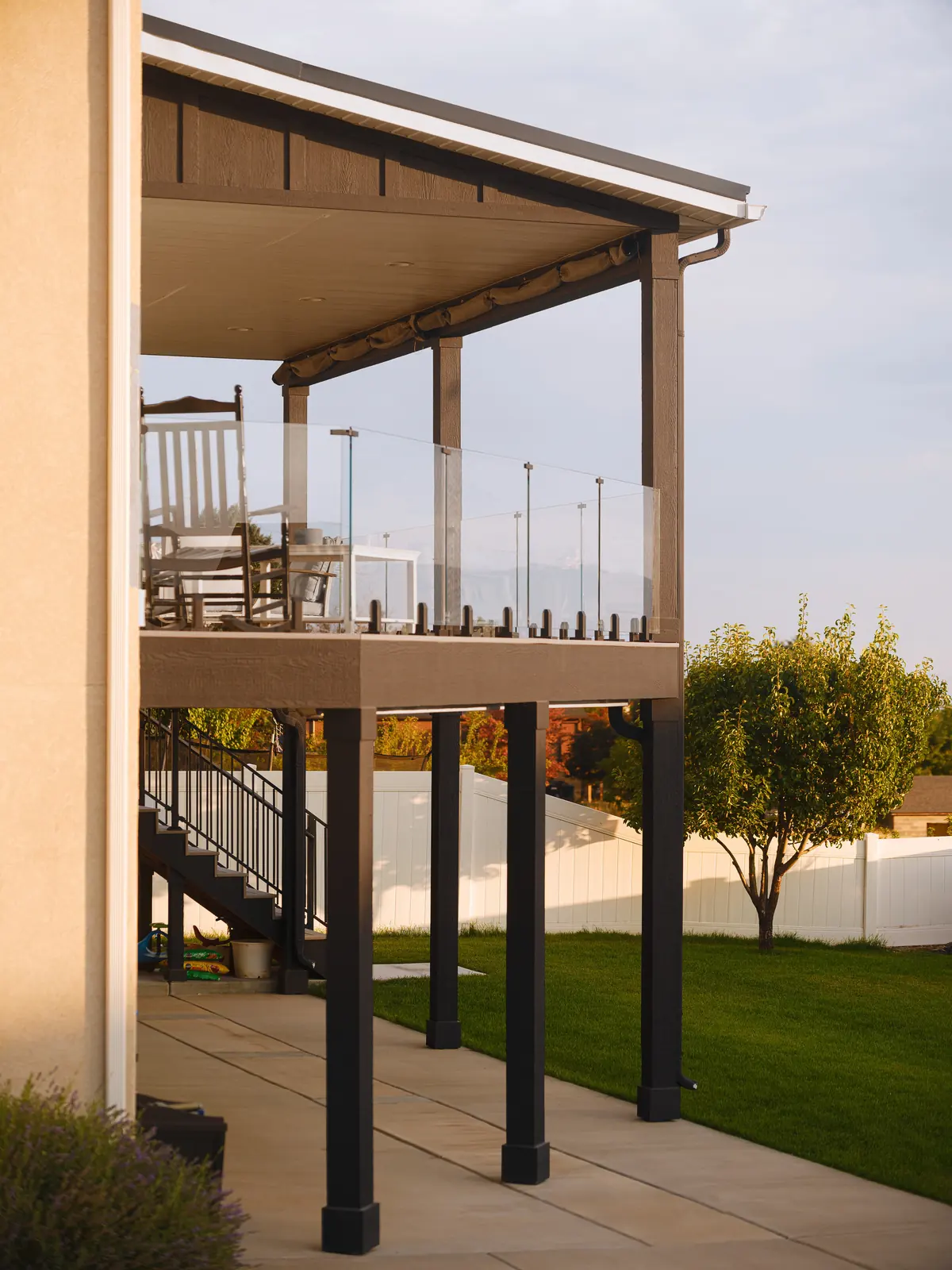 Covered deck with frameless glass railing at sunset