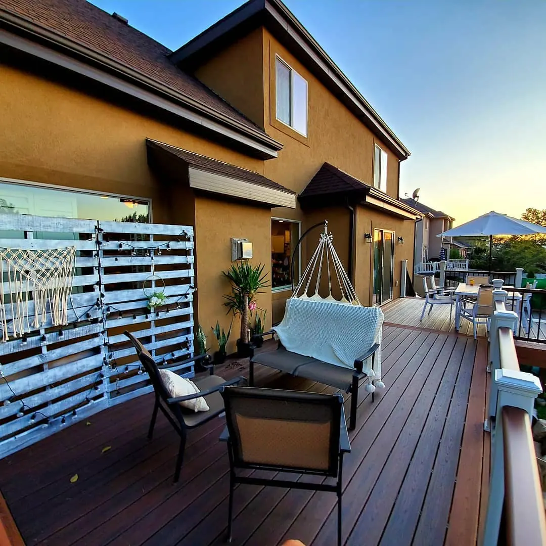 Trex deck lounge area with a hanging chair along the house