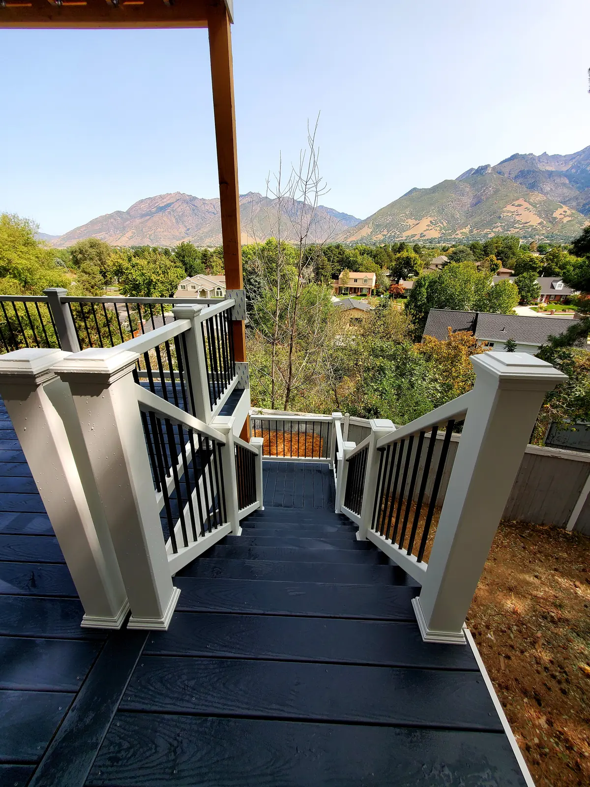 Dark composite deck and stairs with white railing and a mountain view in Provo