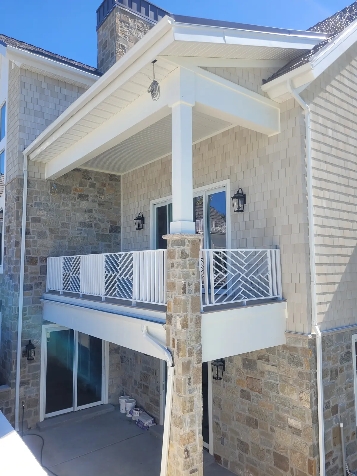 Covered balcony with geometric white railing and stone columns on the same Provo home