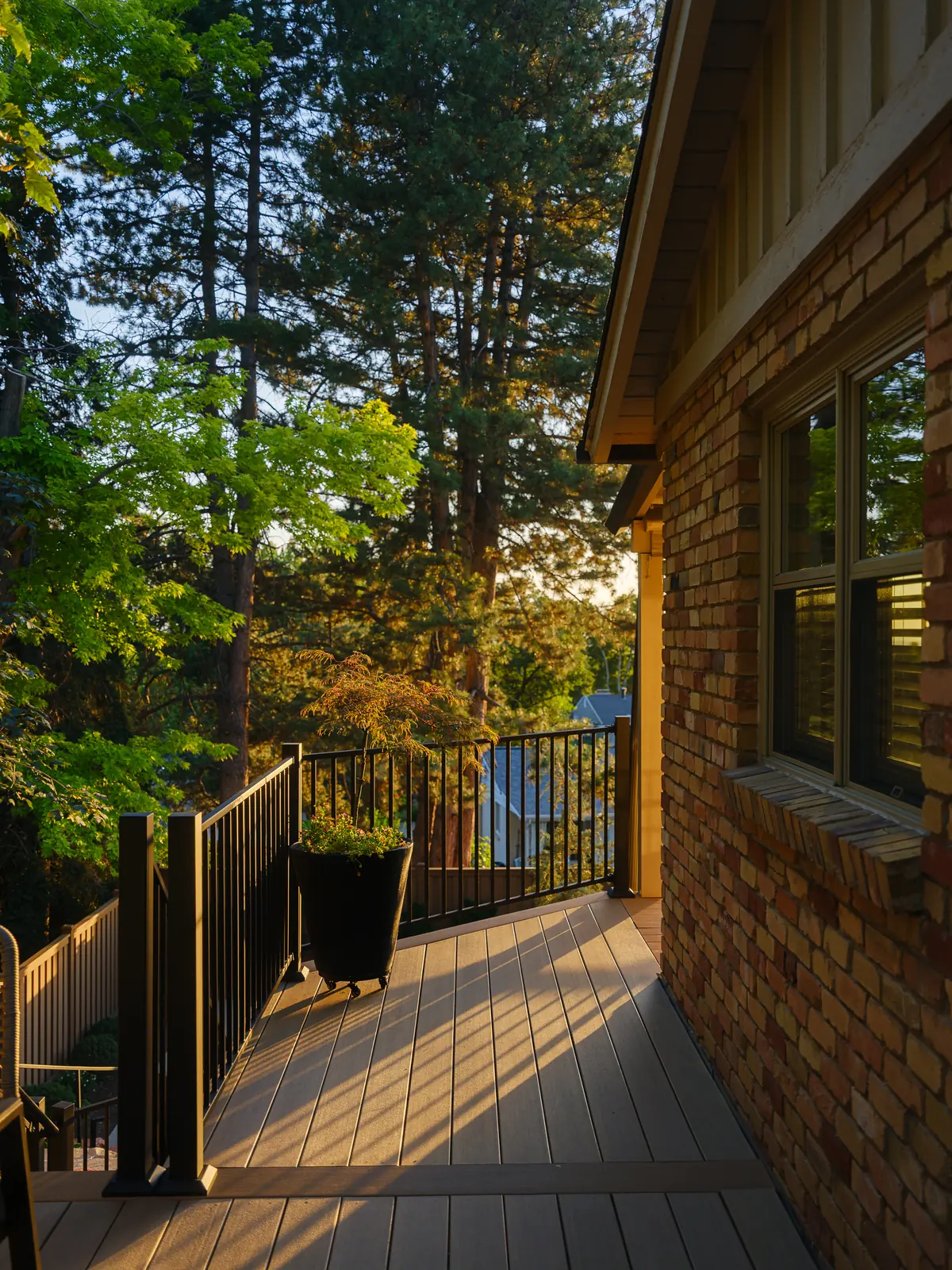 Weathered Teak deck walkway along a brick house with black railing