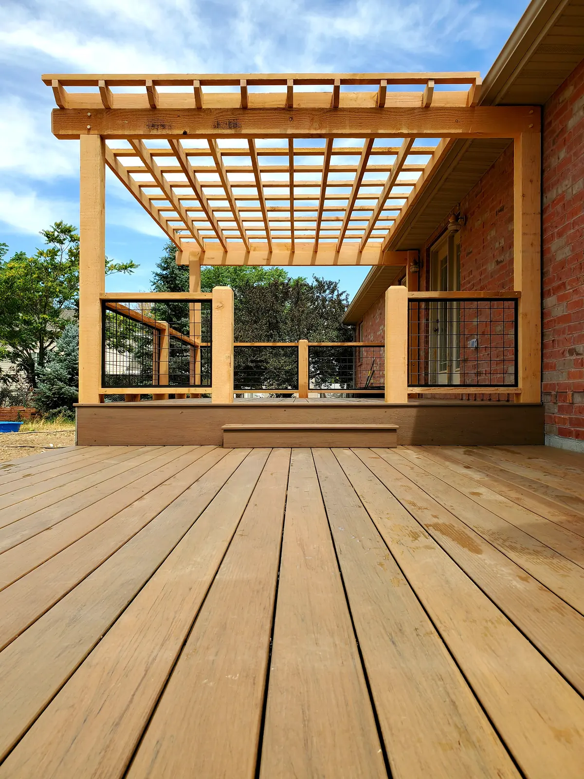 Natural wood pergola over a TimberTech Pecan deck with hog wire railing
