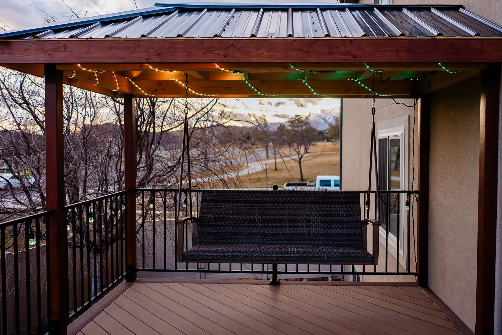 Covered deck corner with a metal roof, string lights and a porch swing