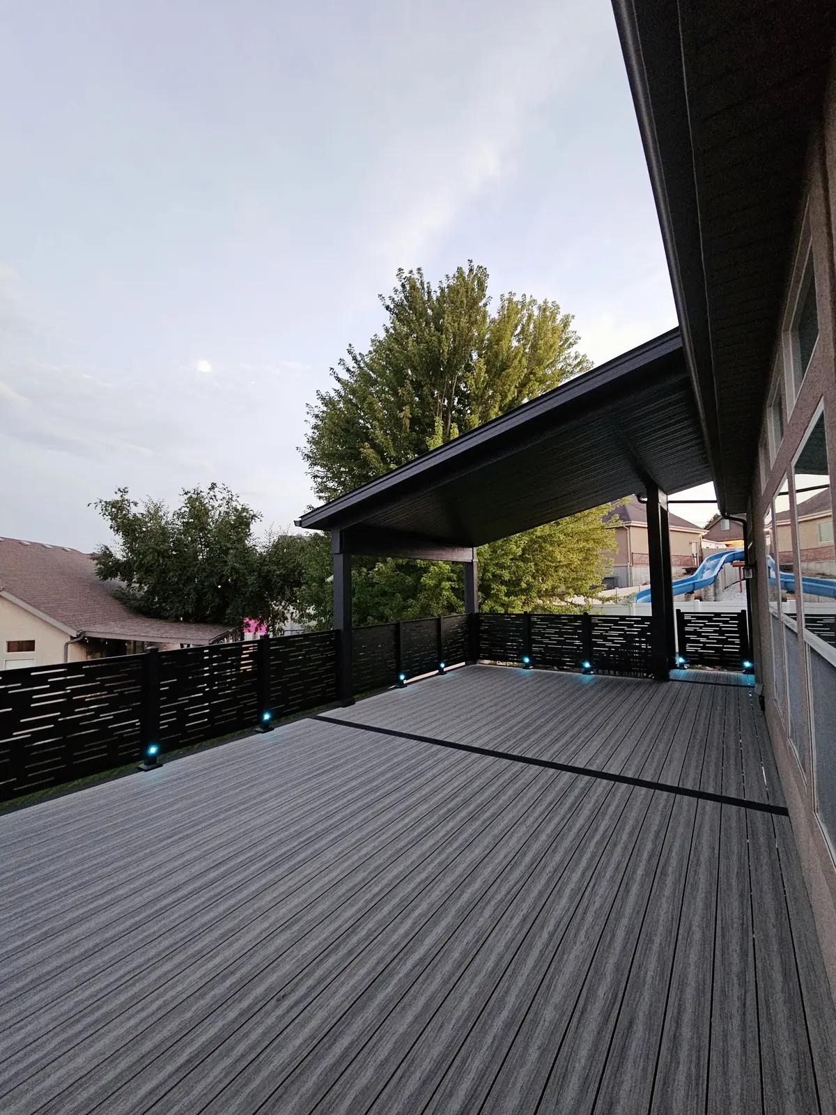 Covered deck with black privacy panels and turquoise post lights