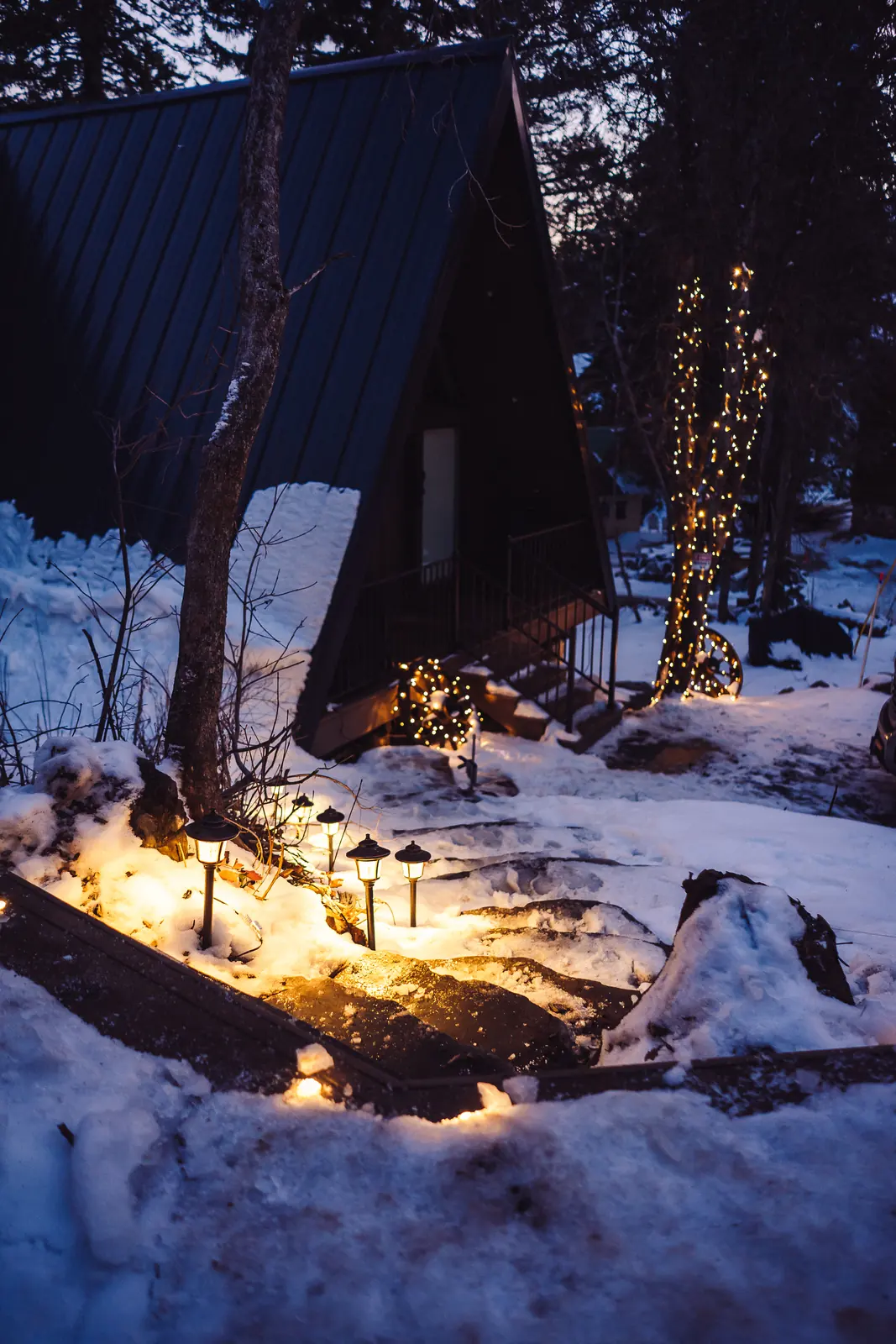 Lit path from an A-frame cabin up to the sauna deck