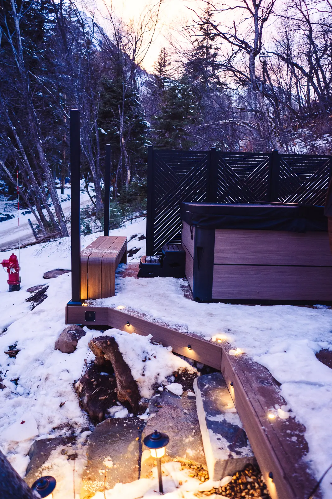 Hot tub deck with privacy screens and a curved bench at a mountain cabin